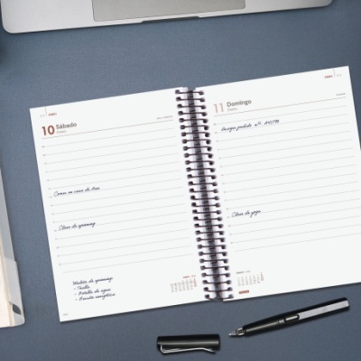 Agenda semanal aberta com anotações e caneta preta em superfície azul