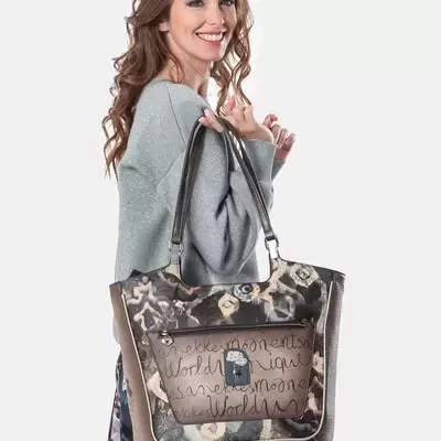 Mulher segurando uma mala tote com estampa floral e bolso frontal com texto manuscrito.