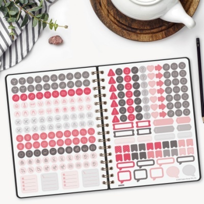 Caderno aberto com autocolantes organizadores coloridos numa mesa branca com chávena e planta