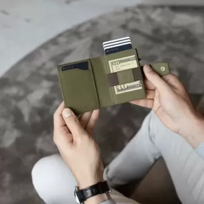 Carteira masculina verde com cartões numa superfície redonda cinzenta