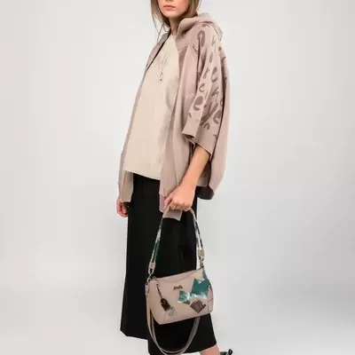 Mulher com capa bege com padrão leopardo e mala bege com detalhes coloridos