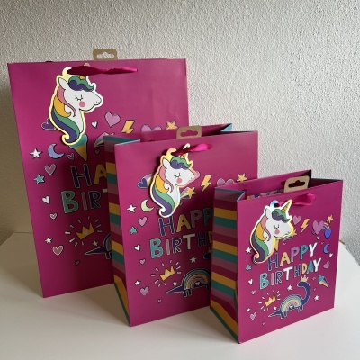Três sacos de presente rosa com unicórnios e texto 'HAPPY BIRTHDAY'