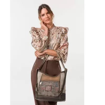 Mulher com blusa estampada e mala de ombro marrom e bege