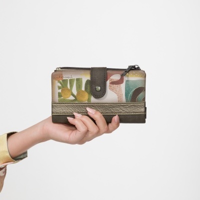 Carteira com padrão colorido sendo segurada numa mão com fundo branco.