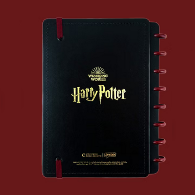 Caderno preto com elásticos vermelhos e texto dourado Harry Potter sobre fundo vermelho