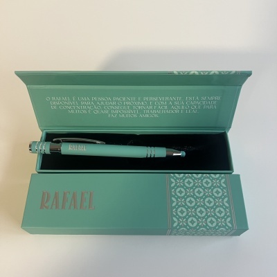 Caneta azul-turquesa com detalhes prateados em caixa azul-turquesa decorada com padrão geométrico branco e nome RAFAEL