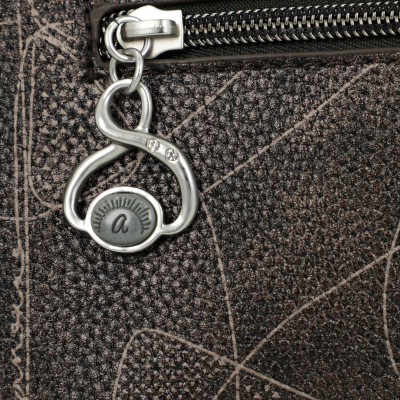 Fecho de zipper prateado com cristais e bolsa castanha texturizada com padrão abstrato