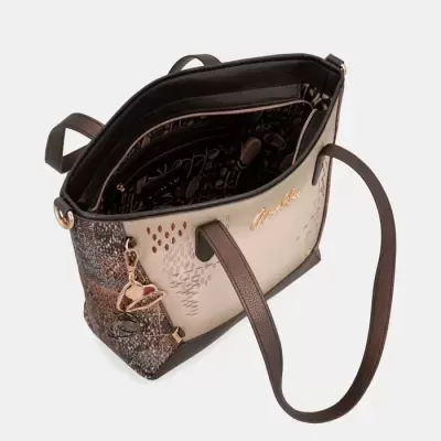 Mala de senhora bege e castanha com padrões e pendente decorativo.