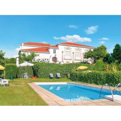 Piscina exterior com casa branca de telhado vermelho ao fundo