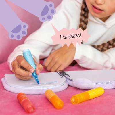 Marcadores coloridos, cadernos felpudos e texto Paw-sitivelly! em ambiente rosa.