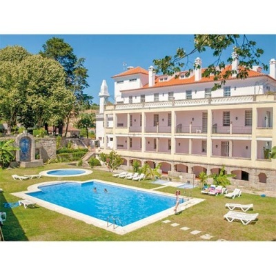 Piscina exterior azul com espreguiçadeiras brancas junto a edifício branco com varandas