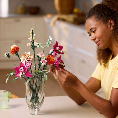 Ramo de flores de peças de construção em vaso de vidro com mulher a segurar uma flor