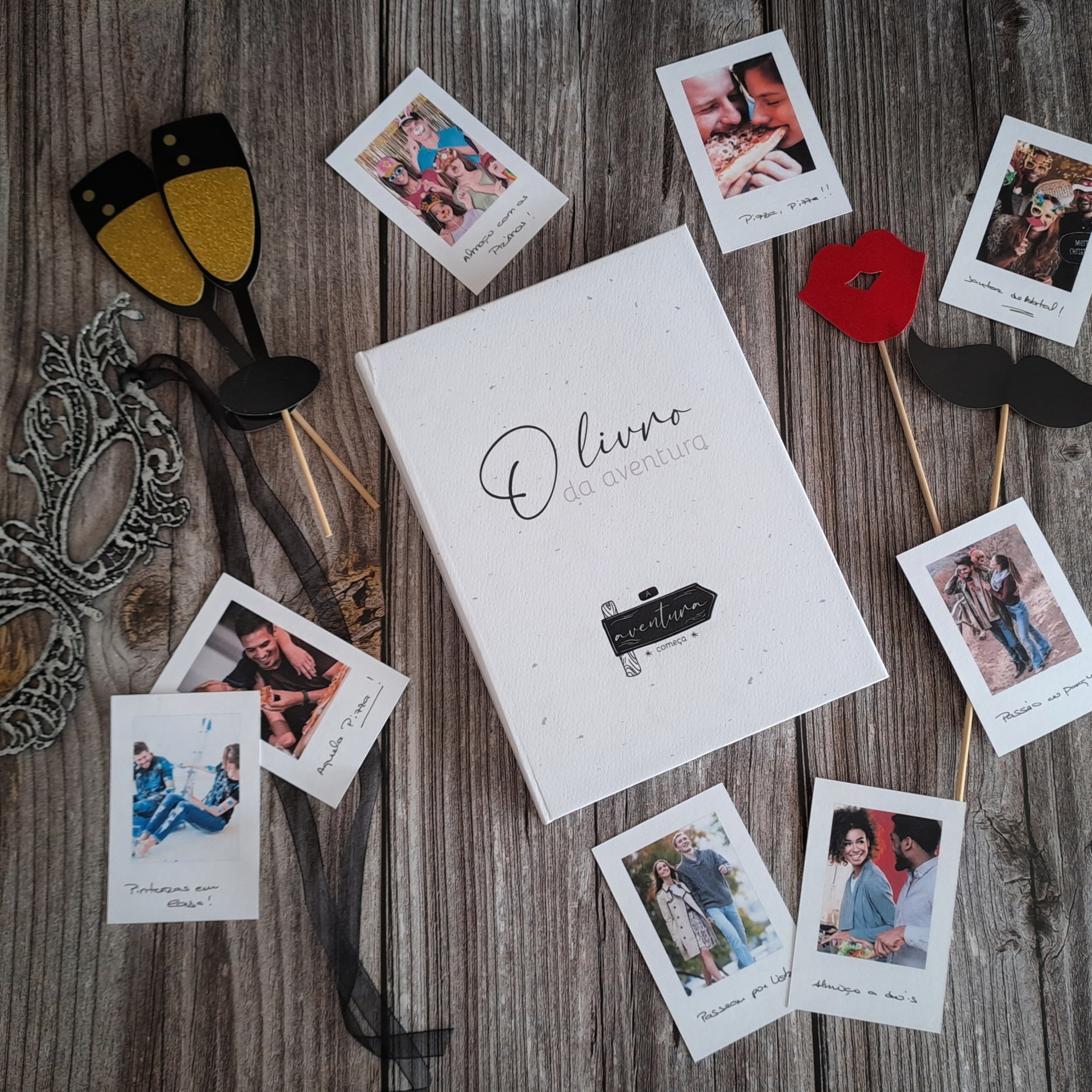 Livro 'O livro da aventura' com fotografias e acessórios para festa sobre madeira