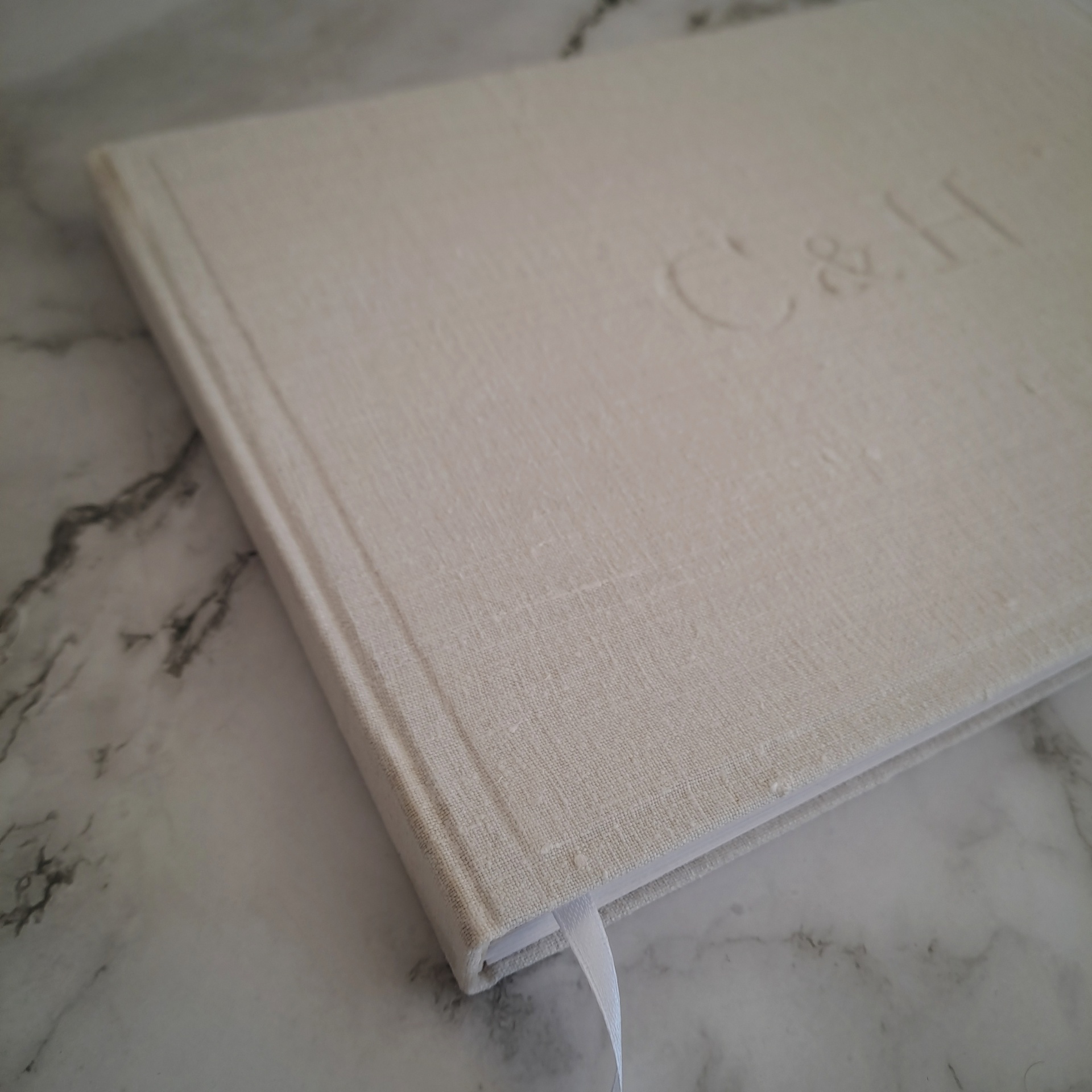 Livro com capa branca texturizada em tecido com letras C & H embutidas