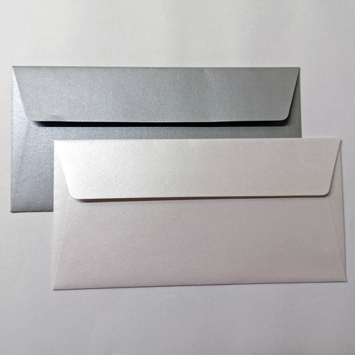 Pacote 50 Envelopes Montesinho Metallic DL dois envelopes retangulares, um prateado e um branco, sobre superfície branca