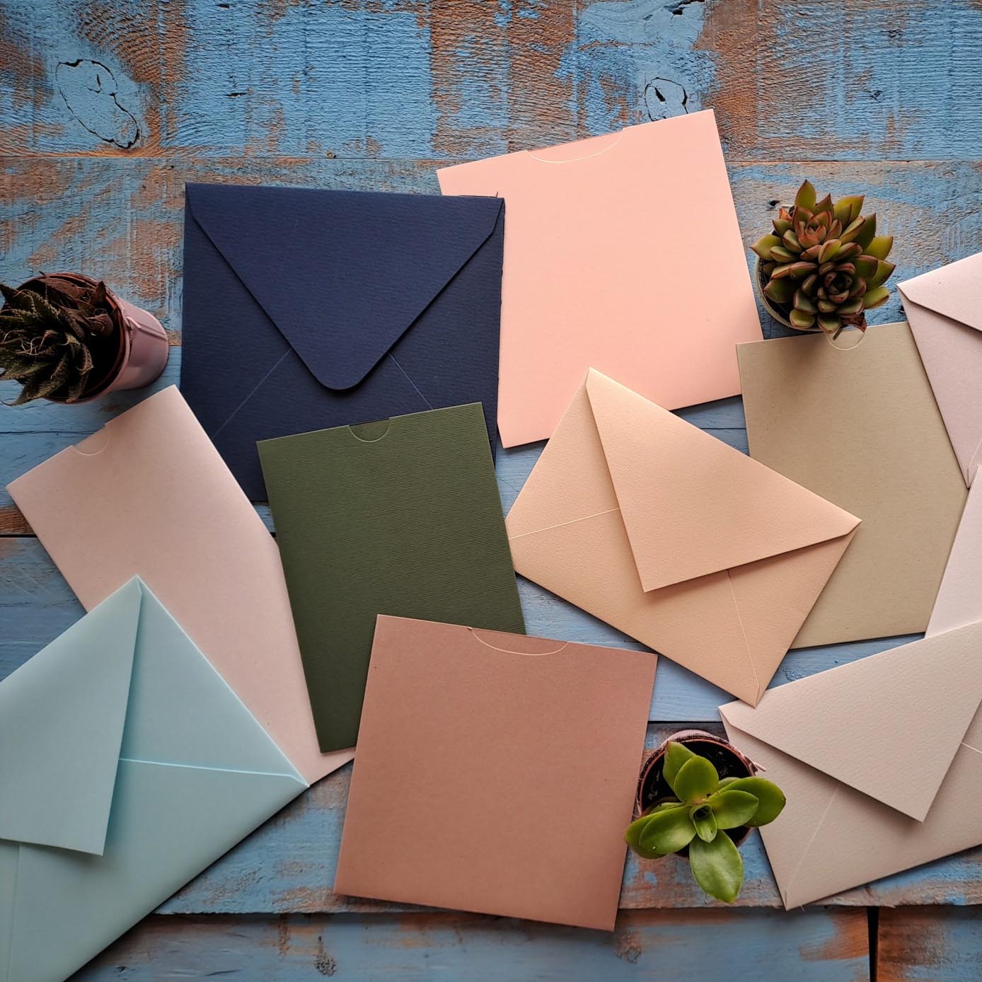 O mundo do papel! Envelopes e cartões coloridos com plantas suculentas sobre madeira azul