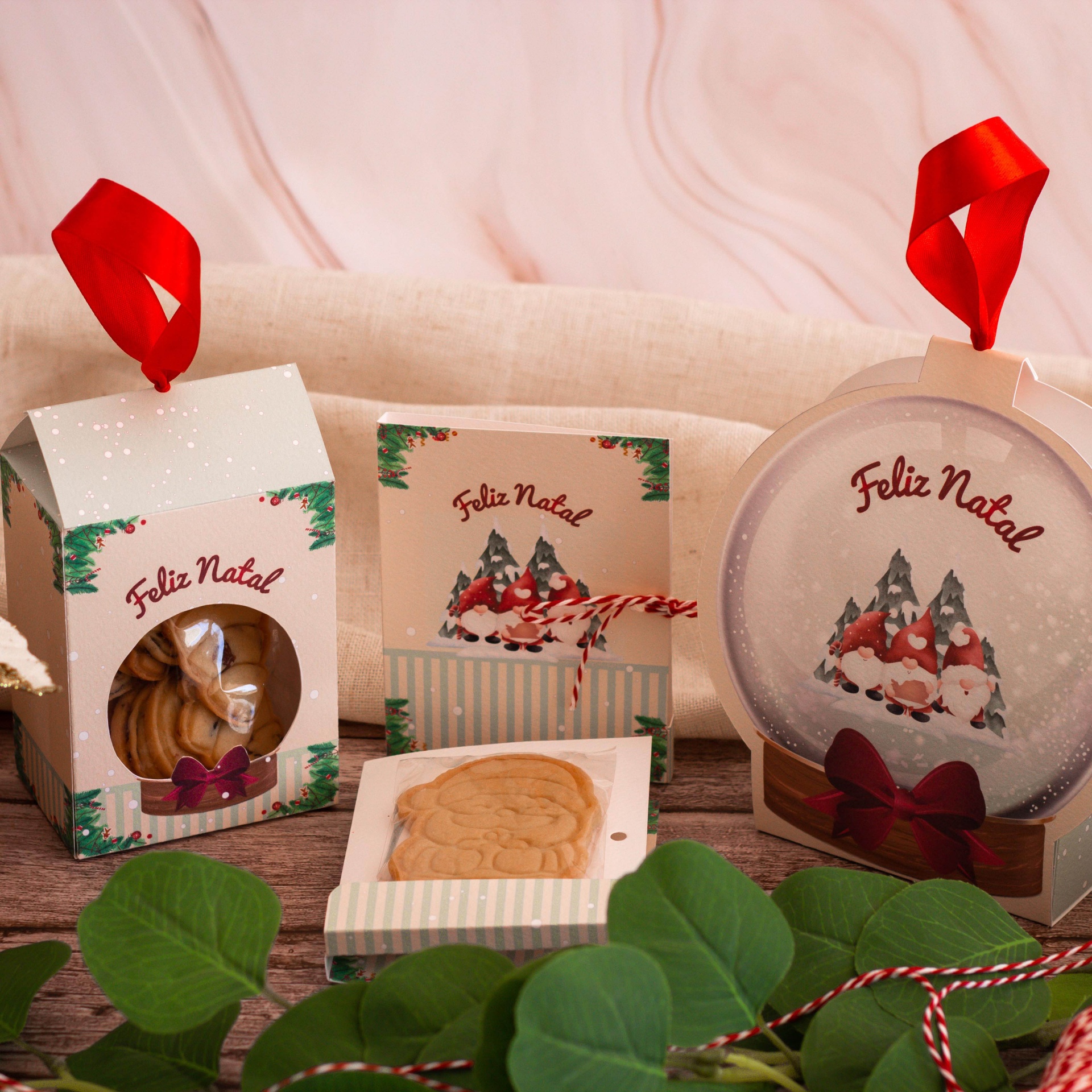 Embalagens festivas com bolachas e ilustrações natalícias de gnomos e árvores em papel com fita vermelha.
