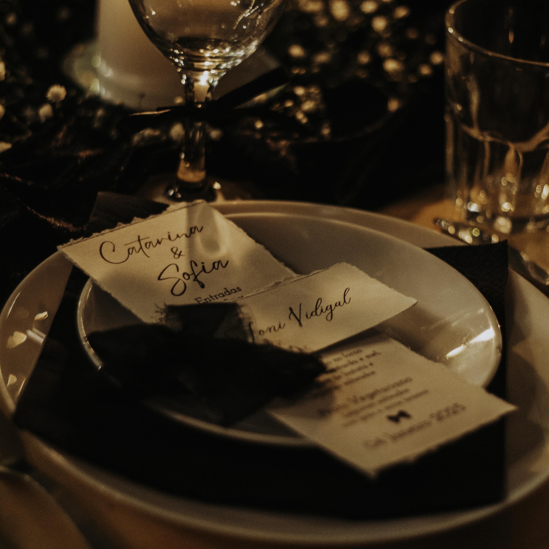 Pratos brancos com guardanapo preto e cartões personalizados com nomes sobre a mesa de jantar