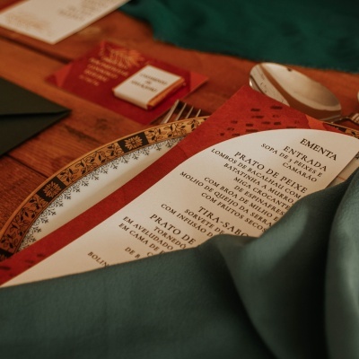 Cardápio vermelho e branco sobre prato decorativo e tecido verde