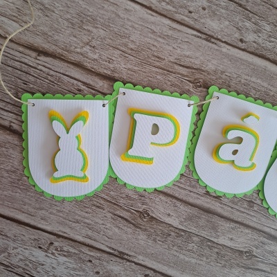Faixa decorativa de papel com letras e coelho em relevo em cima de madeira