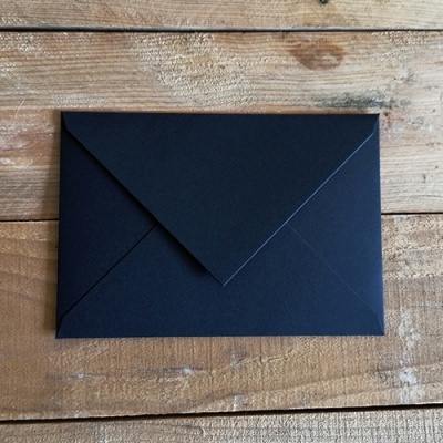 Envelope preto de papel sobre superfície de madeira