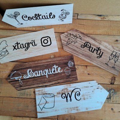 Placas de madeira decorativas com textos e desenhos relacionados a festas, comidas e WC.