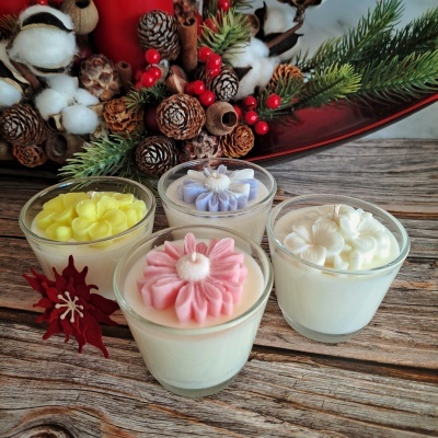 Velas artesanais em copos de vidro com flores coloridas e decoração natural ao fundo