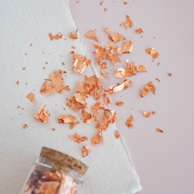 Fragmentos metálicos cobre em fundo branco e rosa com frasco de vidro