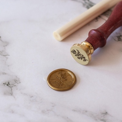 Selo de lacre com cabo em madeira e plástico sobre superfície mármore