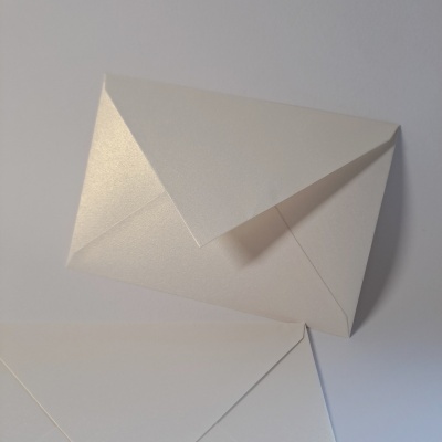 Dois envelopes brancos com textura lisa e brilho sobre superfície branca.