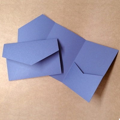 Três envelopes azuis de papel, dois abertos e um fechado, sobre superfície castanha