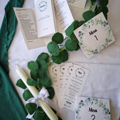 Itens de papelaria para casamento com cartões de mesa, menus, vela branca e folhagem verde