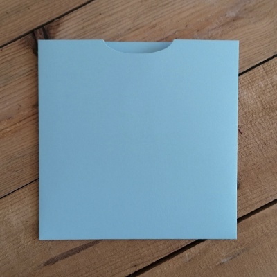 Envelope quadrado azul claro sobre superfície de madeira