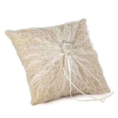 Almofada decorativa bege com renda branca e ornamento central brilhante