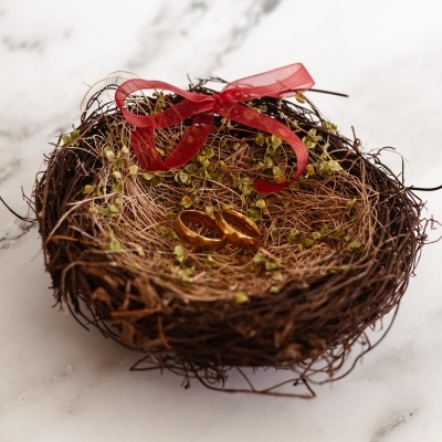 Ninho decorativo com alianças douradas e laço vermelho