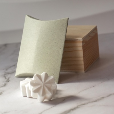 sabonetes brancos em forma de flor com embalagem verde e caixa de madeira