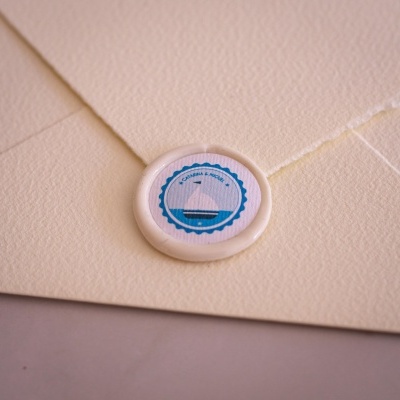 Envelope creme com selo redondo branco e azul com navio desenhado