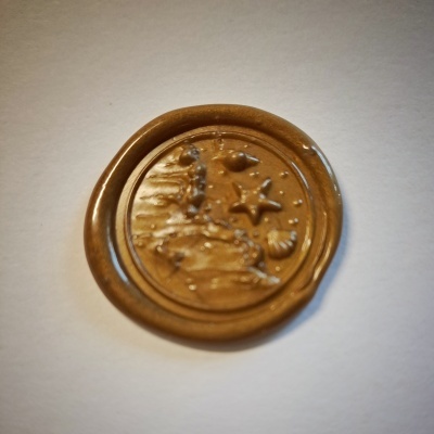 Selo de cera dourada com relevo de símbolos marinhos