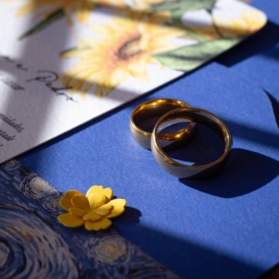 Anéis dourados sobre fundo azul com flores e papéis decorativos