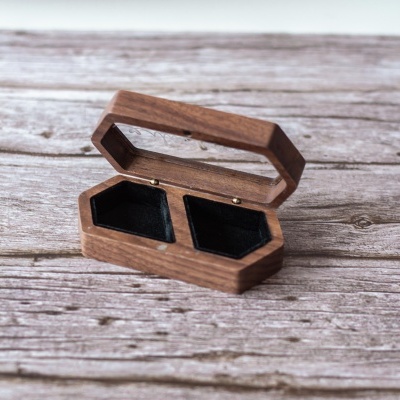 Estojo de madeira castanha com interior preto aberto sobre superfície de madeira