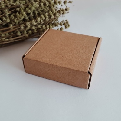 Caixa quadrada pequena de cartão castanho clara com ramo de flores secas ao fundo