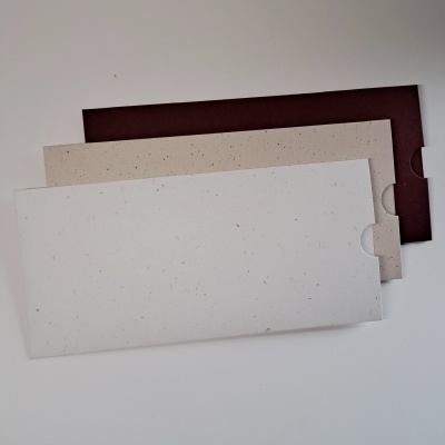 Três envelopes retangulares em papel reciclado branco, bege e castanho