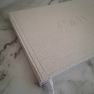Livro com capa branca texturizada em tecido com letras C & H embutidas