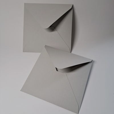 Duas cartas cinzentas abertas em papel texturizado sobre uma superfície branca