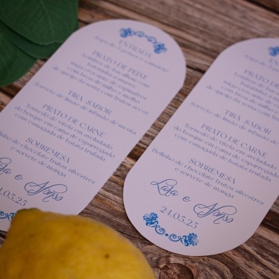 Menus de casamento brancos com texto azul decorativos sobre mesa de madeira com limão