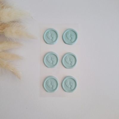 Folha com adesivos verdes água de pegadas de bebé em relevo