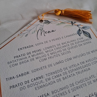 Menu impresso com texto e decoração de folhas com tassel dourado
