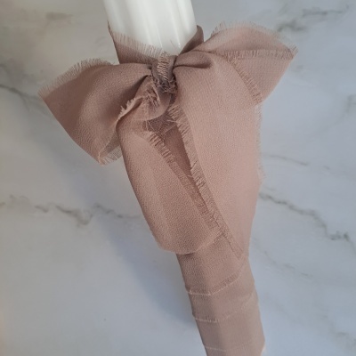 Vela branca com laço de tecido cor de rosa claro e bordas desfiadas