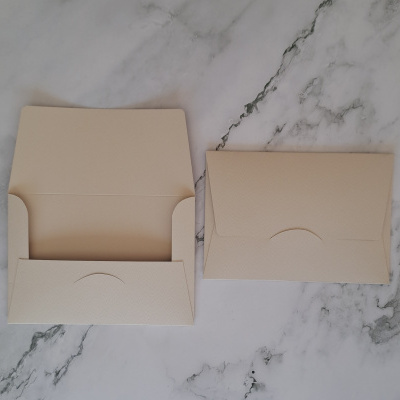 Dois envelopes bege, um aberto e outro fechado, sobre mesa de mármore.