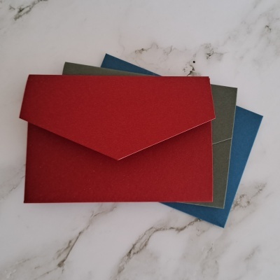 Três envelopes coloridos sobre superfície de mármore